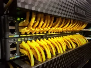 Fila de conmutadores de red de Cisco con numerosos cables Ethernet amarillos conectados.